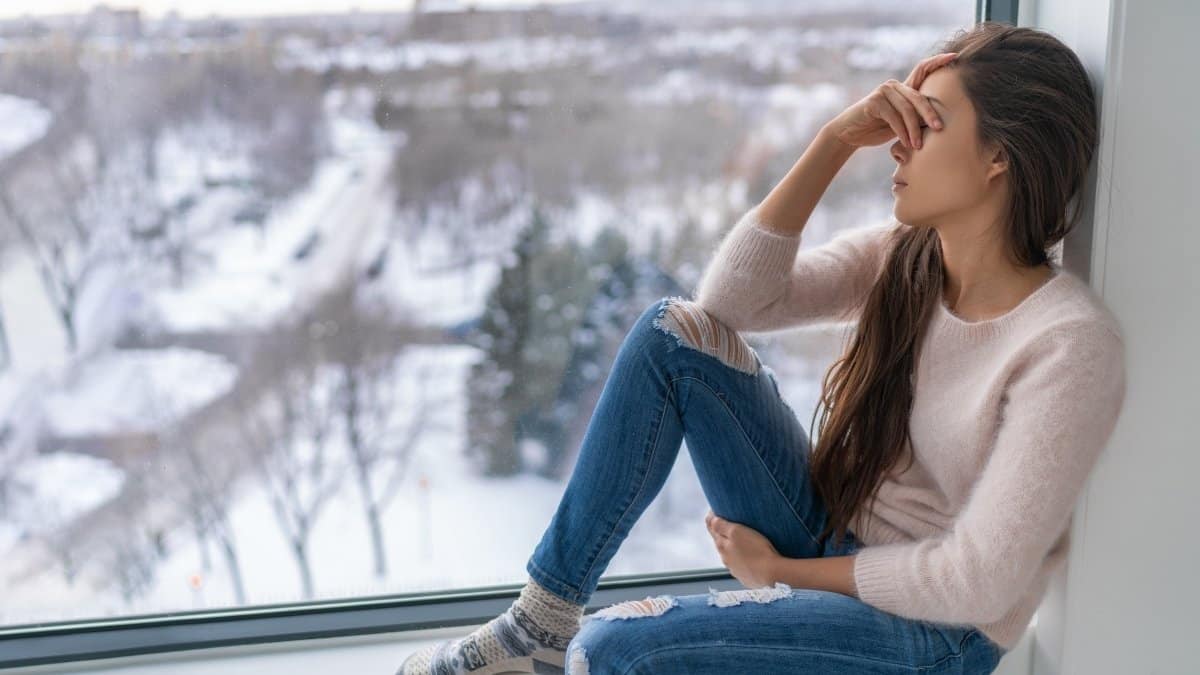 Woman by window suffering from seasonal depression