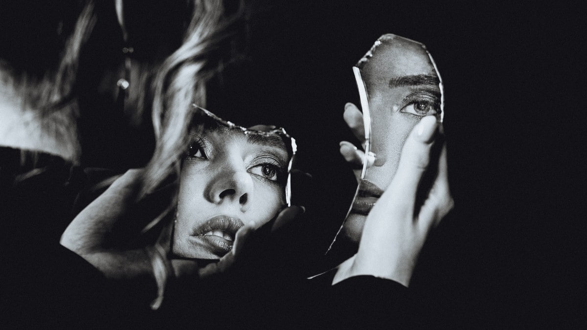 Woman watching herself in broken mirror